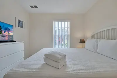 a white bedroom with a bed with towels on it at 8460 CRYSTAL COVE LOOP 3BED in Kissimmee