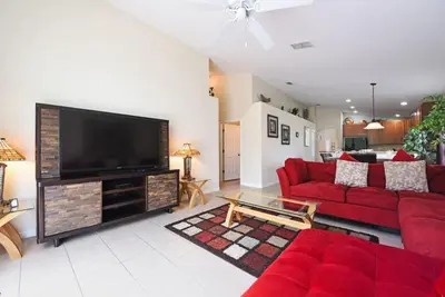 a living room with a red couch and a flat screen tv at Veranda Palms Villa: Pool, Spa & Game Room in Kissimmee