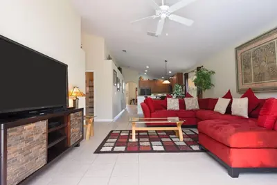 a living room with a red couch and a tv at Veranda Palms Villa: Pool, Spa & Game Room in Kissimmee