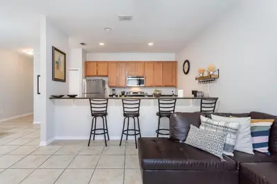 a living room with a couch and a kitchen at 4BR Retreat with Resort Access and Pool in Kissimmee