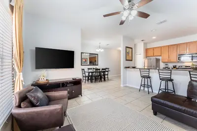 a living room with a couch and chairs and a kitchen at 4BR Retreat with Resort Access and Pool in Kissimmee