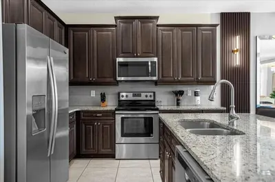 a kitchen with wooden cabinets and stainless steel appliances at Awsome 8 Bd 6.5 Ba Sleeps 20 Encore in Orlando