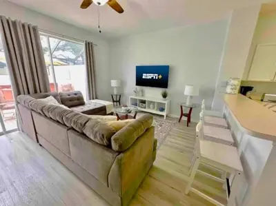 a living room with a couch and a flat screen tv at Your Cozy 3 BD Home w Private Hot Tub & BBQ Gril in Kissimmee