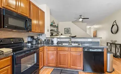 a kitchen with wooden cabinets and black appliances at Cozy Home with 3BD & BBQ Grill in Orlando