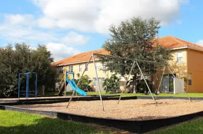 a playground with a swing set in front of a building at Cozy Home with 3BD & BBQ Grill in Orlando