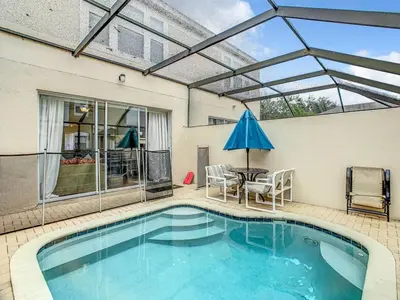a swimming pool with a patio with a table and a blue umbrella at Windsor Palms Townhome w/Private Pool Near Disney in Kissimmee
