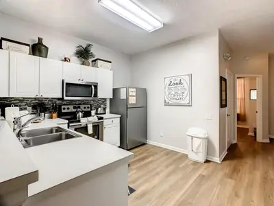 a kitchen with white cabinets and a stainless steel refrigerator at Windsor Palms Townhome w/Private Pool Near Disney in Kissimmee
