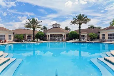 a large swimming pool with palm trees and a building at Windsor Palms Townhome w/Private Pool Near Disney in Kissimmee