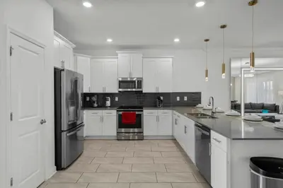 a kitchen with white cabinets and stainless steel appliances at Storey Lake, 24 hóspedes, 9Q, piscina e vista lago in Kissimmee
