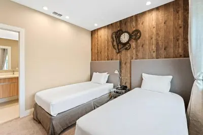 two beds in a room with a clock on the wall at Magic Village 4 suítes 8 min da Disney perto da 192 in Orlando
