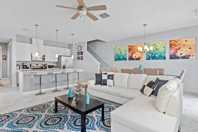 a living room with a white couch and a kitchen at Compass Bay: 4Q reformados Perto da Disney! in Kissimmee