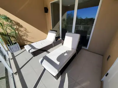 two lounge chairs and a couch on a balcony at Magic Village Casa com 4 Suítes - 8 min da Disney! in Orlando