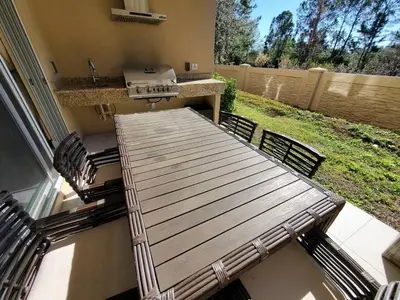 a wooden table and chairs on a patio with a grill at Magic Village Casa com 4 Suítes - 8 min da Disney! in Orlando
