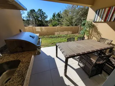 a patio with a grill and a picnic table at Magic Village Casa com 4 Suítes - 8 min da Disney! in Orlando