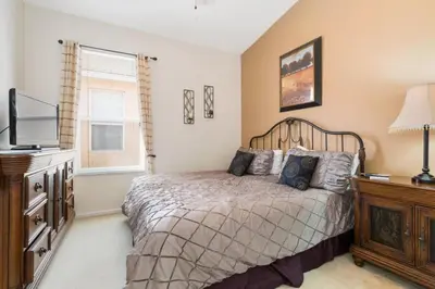 a bedroom with a bed and a dresser and a television at Windsor Palms Villa: Pool & Close to Disney in Kissimmee