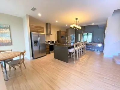 a kitchen and dining room with a table and chairs at 7562 Magic Village: 4 Suítes, 8 Hóspedes, Apenas 8 Minutos da Disney! in Orlando