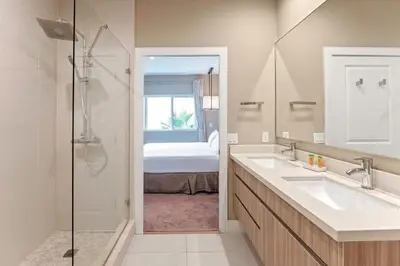 a bathroom with two sinks and a shower with a bed at 7562 Magic Village: 4 Suítes, 8 Hóspedes, Apenas 8 Minutos da Disney! in Orlando