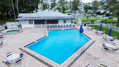 a large swimming pool with chairs and a house at New! Family cottage near Disney-Sleep 6 in Kissimmee