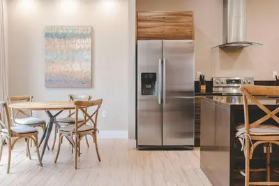 a kitchen with a table and a stainless steel refrigerator at 6 min da Disney • Casa Moderna 4 Suítes c/ BBQ in Orlando