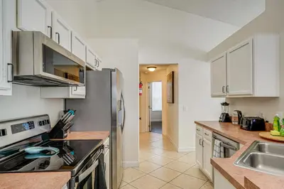 a kitchen with white cabinets and a stainless steel refrigerator at 9 Mi to Disney Home with Pool Table and Water Views! in Kissimmee