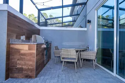 a patio with a table and chairs and some windows at Beautiful 4BD home Themed Pool and Grill 4403 in Kissimmee