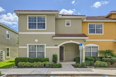 a large house with bushes in front of it at Luxury 5BR Townhome w Pool & Resort Access in Kissimmee