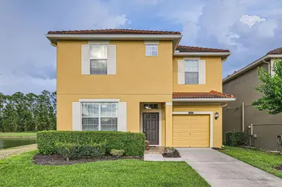 a large yellow house with a garage at Spacious 6BR Villa w Pool, Game Room & View in Kissimmee