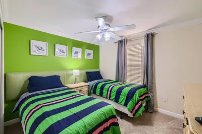 two beds in a room with green walls at Spacious 6BR Villa w Pool, Game Room & View in Kissimmee