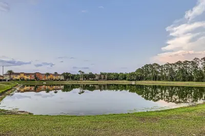 a large pond in a field with houses in the background at Spacious 6BR Villa w Pool, Game Room & View in Kissimmee