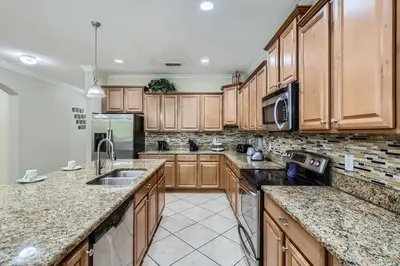 a kitchen with wooden cabinets and granite counter tops at Spacious 6BR Villa w Pool, Game Room & View in Kissimmee