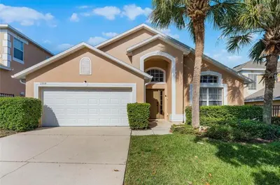 a house with a garage and a palm tree at Ultimate family resort home with incredible sunset views, 4 miles from Disney! in Kissimmee