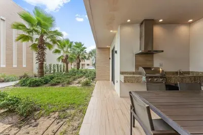 a patio with a table and a grill and palm trees at 7545 Magic Village - Charmoso e especial, a 6 minutos da Disney in Orlando