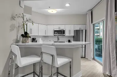 a kitchen with white cabinets and white bar stools at 3 Bedroom Family Friendly Condo at WorldQuest near Disney 2714 in Orlando