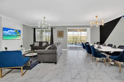 a living room with a table and blue chairs at Serenity Lakeview Retreat Stunning Water Views, No Rear Neighbors, Private Pool, Game Room Star Wars Cinema in Kissimmee