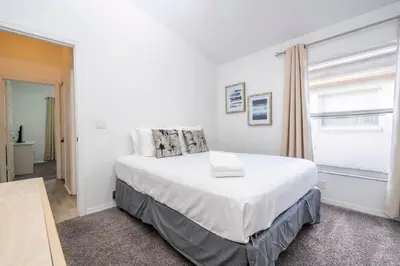 a white bedroom with a large bed and a window at Near Disney with Pool and BBQ 4BD Single House in Kissimmee