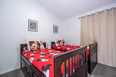 a bedroom with a bed with a red comforter at Near Disney with Pool and BBQ 4BD Single House in Kissimmee