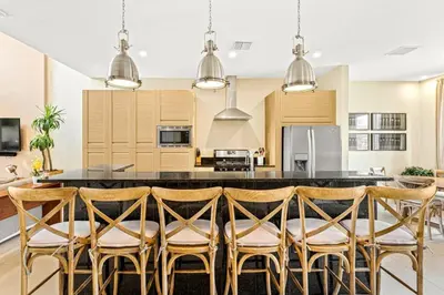 a kitchen with a large island with bar chairs at 3212 Magic Village - 8 hóspedes, à beira do lago, 8 minutos da Disney in Orlando