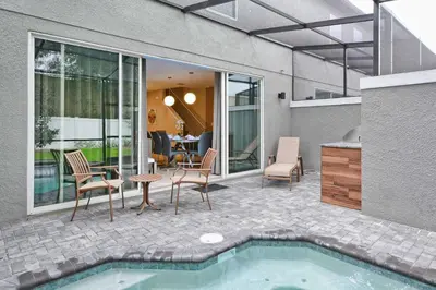 a patio with a pool and chairs and a table at Beautiful 4BD home Themed Pool and Grill 4417 in Kissimmee