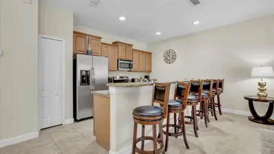 a kitchen with a bar with chairs and a refrigerator at CAL8959 in Kissimmee