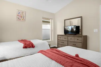 a bedroom with two beds and a television on a dresser at Spacious Disney Retreat with pool & parking in Kissimmee