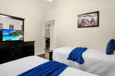 a bedroom with two beds and a tv on the wall at Spacious Disney Retreat with pool & parking in Kissimmee
