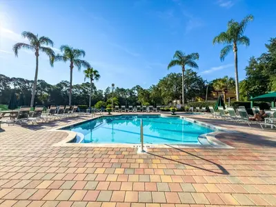 a swimming pool with chairs and palm trees at LDK2787 in Kissimmee