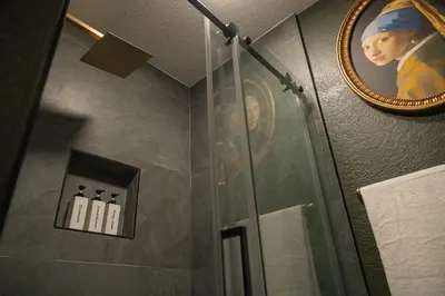 a shower in a bathroom with a painting on the wall at Historic Orlando Casita Love Apt A with backyard in Orlando
