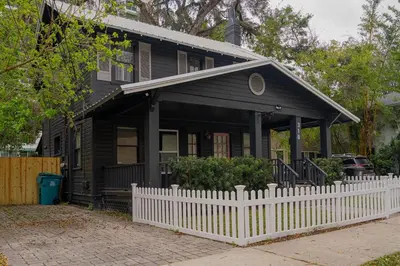 a black house with a white fence in front of it at Historic Orlando Casita Love Apt A with backyard in Orlando