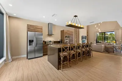 a kitchen and living room with a stainless steel refrigerator at Casa 3 Suítes c/ Jacuzzi e Churrasq. — Disney 6min in Orlando