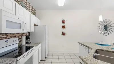 a kitchen with white cabinets and a refrigerator at Spacious Family Townhouse Sleeps 8 in Kissimmee