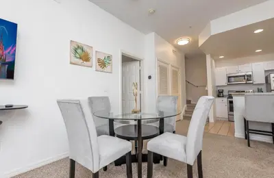 a dining room with a glass table and white chairs at Spectacular townhouse with themed room in Kissimmee