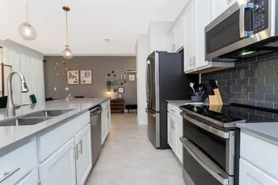 a kitchen with white cabinets and black appliances at La Vita E Bella 4 Bedroom Storey Lake Condo in Kissimmee