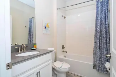a white bathroom with a sink and a toilet at Stunning Game Room & Pool Jacuzzi Storey Lake 2799 in Kissimmee
