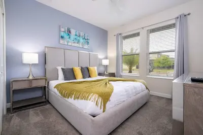 a bedroom with a large bed and two windows at Stunning Game Room & Pool Jacuzzi Storey Lake 2799 in Kissimmee